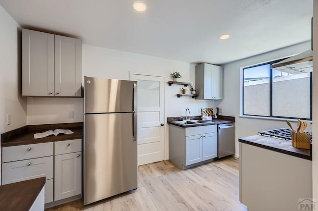 kitchen with open shelves, recessed lighting, light wood-style flooring, appliances with stainless steel finishes, and a sink