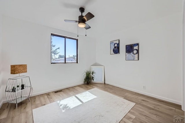 empty room with ceiling fan, baseboards, and wood finished floors