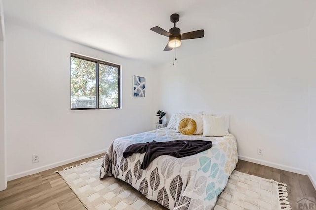 bedroom featuring ceiling fan, baseboards, and wood finished floors