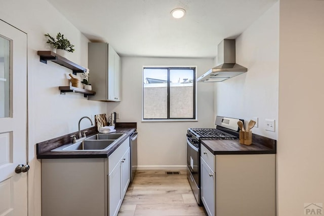 kitchen featuring dark countertops, wall chimney range hood, open shelves, and stainless steel appliances