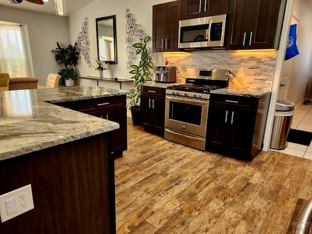 1044 S Los Charros Dr, Pueblo West, CO 81007 - kitchen featuring tasteful backsplash, appliances with stainless steel finishes, light wood-style floors, and light stone countertops