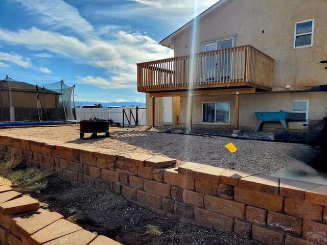 1044 S Los Charros Dr, Pueblo West, CO 81007 - back of house with a balcony, stucco siding, a trampoline, and fence