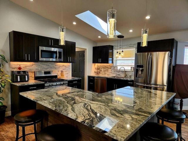 1044 S Los Charros Dr, Pueblo West, CO 81007 - kitchen featuring wood finished floors, a spacious island, a sink, appliances with stainless steel finishes, and lofted ceiling with skylight