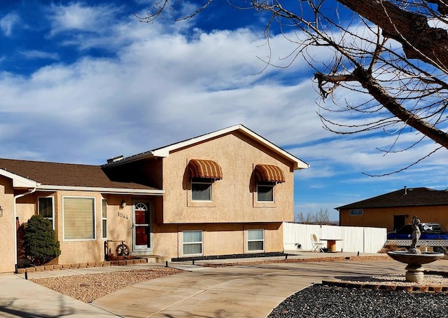 view of front facade with fence and stucco siding