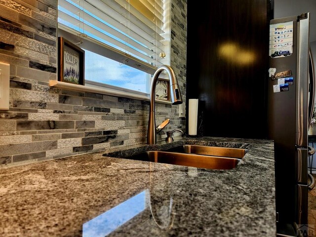 1044 S Los Charros Dr, Pueblo West, CO 81007 - details featuring a sink, decorative backsplash, stone counters, and freestanding refrigerator