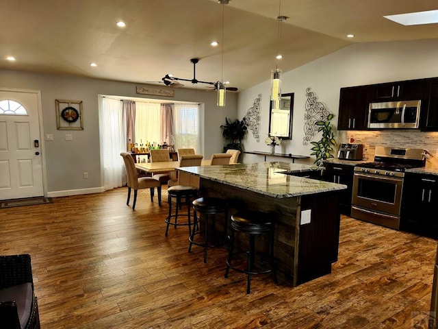 1044 S Los Charros Dr, Pueblo West, CO 81007 - kitchen featuring dark wood-style floors, appliances with stainless steel finishes, a breakfast bar, and a center island