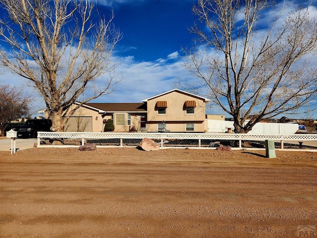 1044 S Los Charros Dr, Pueblo West, CO 81007 - split level home featuring concrete driveway, an attached garage, and fence