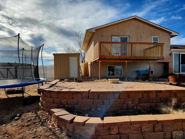 1044 S Los Charros Dr, Pueblo West, CO 81007 - rear view of house with a trampoline, stucco siding, a storage shed, a deck, and an outdoor structure