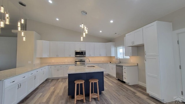 kitchen with light stone counters, stainless steel appliances, a peninsula, and white cabinets