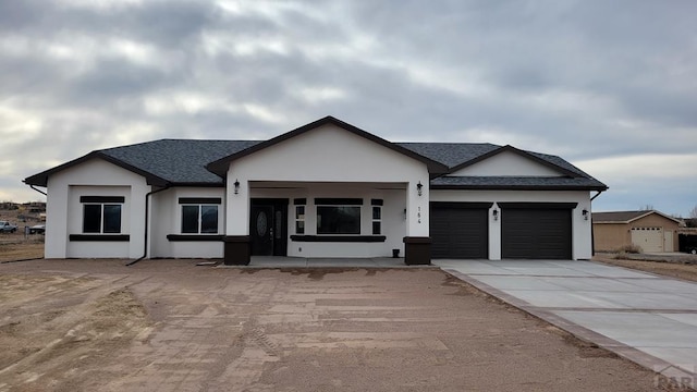 view of front of house featuring stucco siding, driveway, an attached garage, and a shingled roof