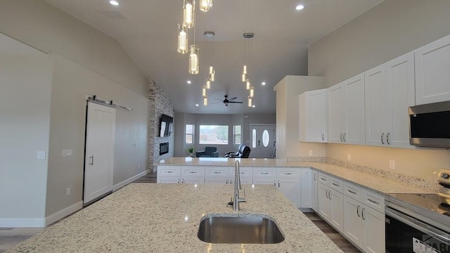 kitchen with a sink, dark wood finished floors, appliances with stainless steel finishes, white cabinets, and lofted ceiling