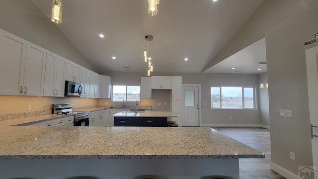 kitchen featuring white cabinetry, a peninsula, light stone counters, and appliances with stainless steel finishes