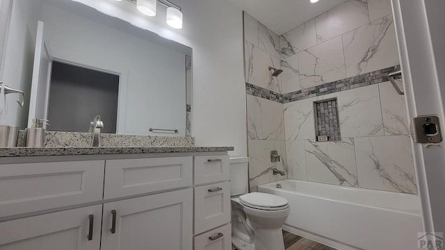 bathroom with vanity, toilet, wood finished floors, and shower / bath combination