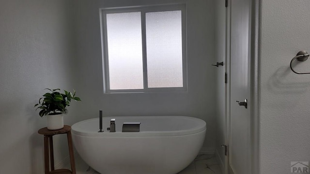 bathroom with a soaking tub and marble finish floor