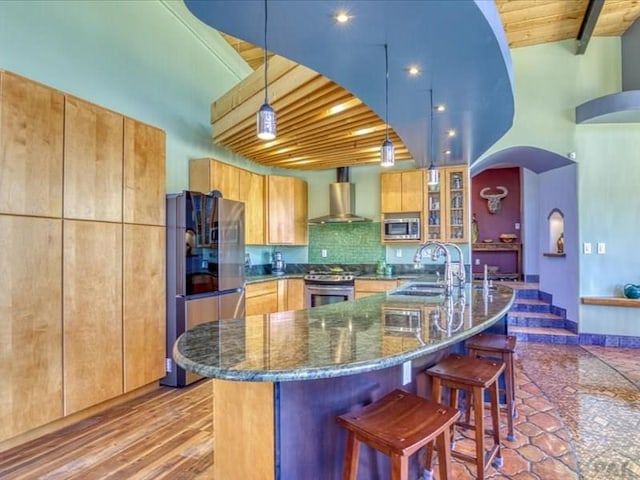 1441 Forest Rd Unit 507 1A, Creede, CO 81130 - kitchen featuring appliances with stainless steel finishes, wall chimney exhaust hood, a sink, dark stone countertops, and a kitchen bar