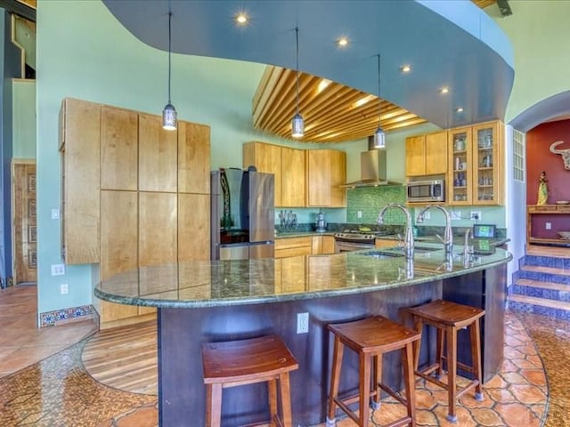 1441 Forest Rd Unit 507 1A, Creede, CO 81130 - kitchen with appliances with stainless steel finishes, wall chimney exhaust hood, dark stone countertops, a kitchen breakfast bar, and a sink