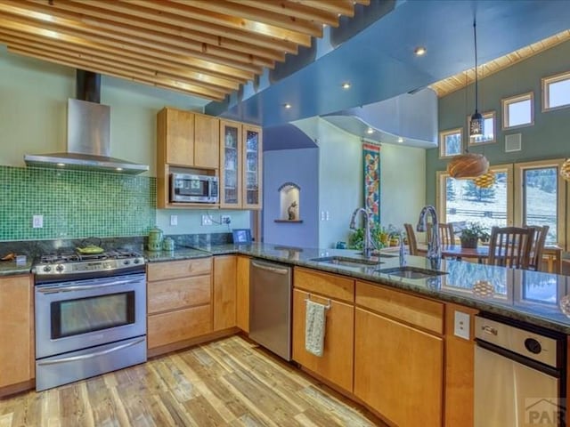 1441 Forest Rd Unit 507 1A, Creede, CO 81130 - kitchen featuring stainless steel appliances, wall chimney exhaust hood, dark stone countertops, light wood-style floors, and backsplash