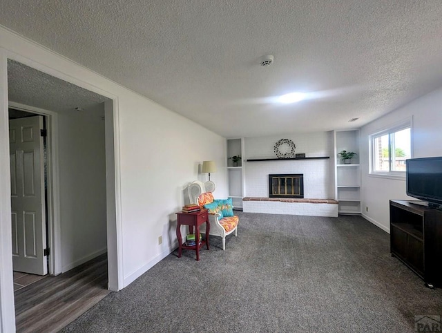 carpeted living room with baseboards, a fireplace, and a textured ceiling