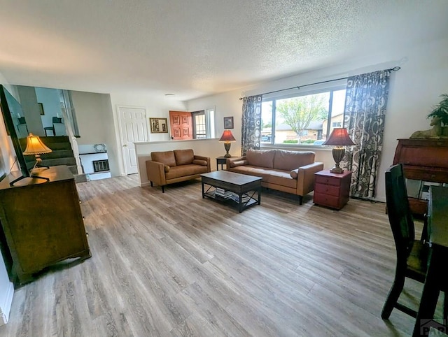 living room featuring baseboards, light wood-style flooring, and a textured ceiling