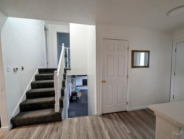 staircase featuring baseboards and wood finished floors