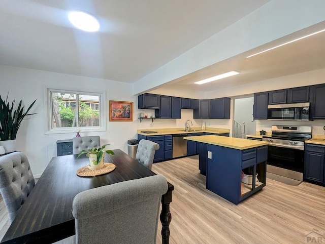 kitchen with light countertops, a kitchen island, stainless steel appliances, and light wood-type flooring