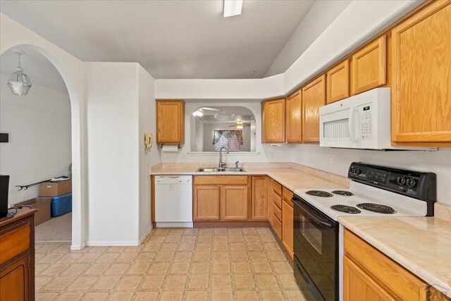 kitchen with white appliances, arched walkways, light countertops, light floors, and a sink