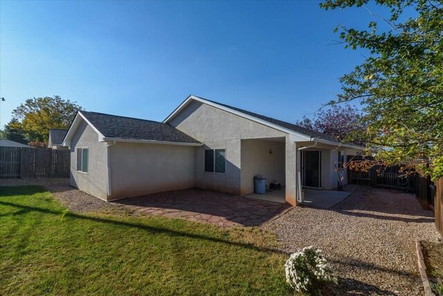 rear view of house featuring a fenced backyard, a patio, a lawn, and stucco siding