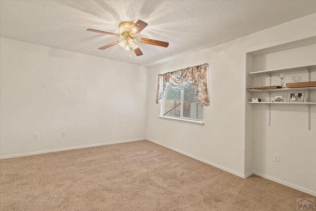 empty room with a textured ceiling, baseboards, a ceiling fan, and light colored carpet