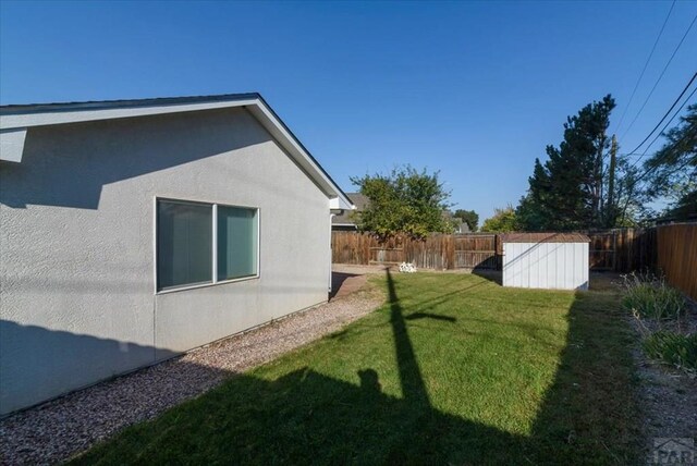 view of yard featuring an outbuilding, a fenced backyard, and a storage unit