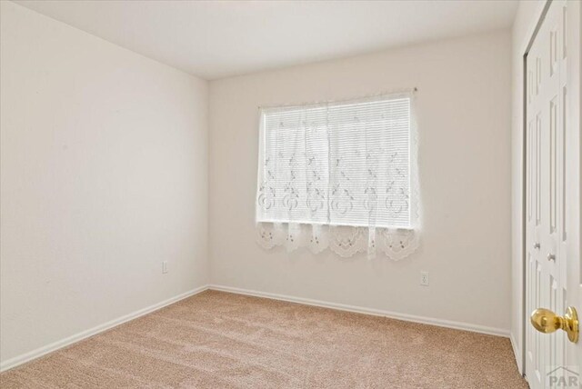 empty room featuring baseboards and light colored carpet