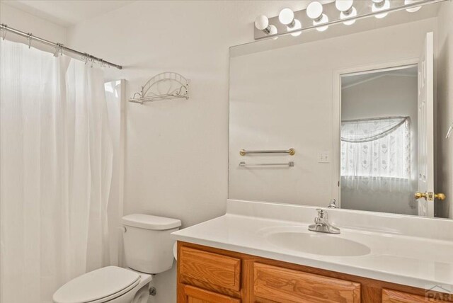 bathroom featuring toilet, curtained shower, and vanity