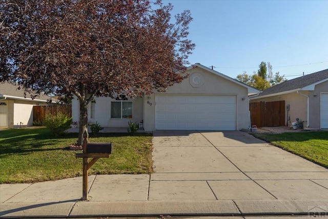 view of front of home with a garage, fence, concrete driveway, stucco siding, and a front yard