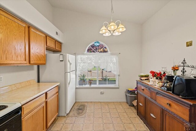 kitchen with a chandelier, light countertops, freestanding refrigerator, brown cabinets, and light floors