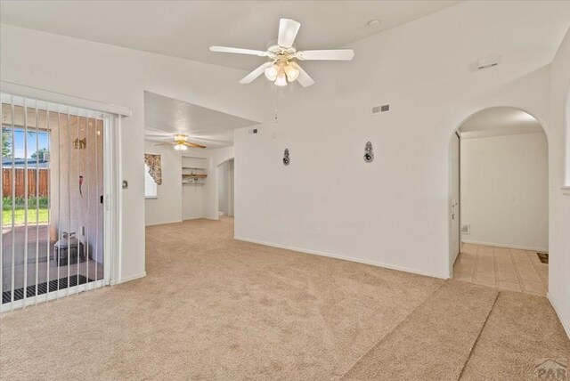 spare room with arched walkways, light carpet, visible vents, baseboards, and a ceiling fan