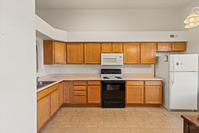 kitchen with light countertops, visible vents, brown cabinetry, a sink, and white appliances