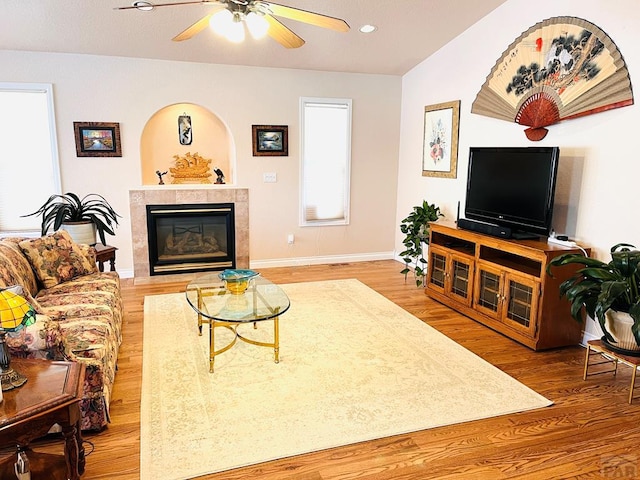living area with ceiling fan, a tile fireplace, baseboards, recessed lighting, and light wood-style flooring