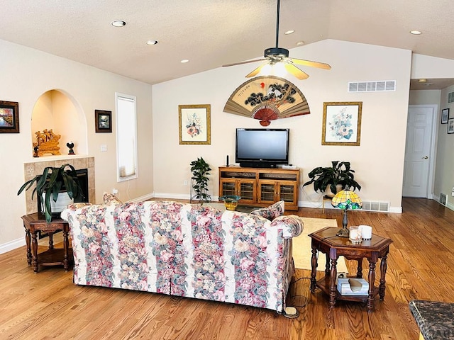 living area featuring ceiling fan, vaulted ceiling, light wood-style flooring, and visible vents