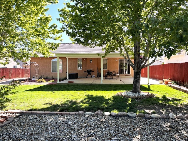 rear view of property with fence, central air condition unit, stucco siding, a lawn, and a patio