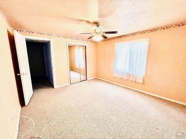 empty room with a ceiling fan, baseboards, light colored carpet, and a textured ceiling