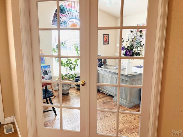 doorway to outside with visible vents, lofted ceiling, wood finished floors, and french doors