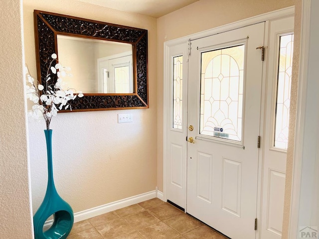 entryway with light tile patterned floors, baseboards, and plenty of natural light