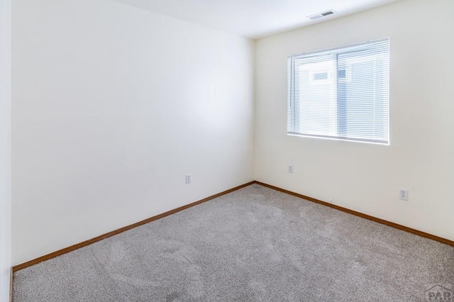 empty room featuring carpet floors, visible vents, and baseboards