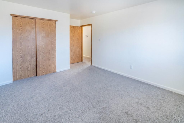 unfurnished bedroom with carpet floors, a closet, and baseboards