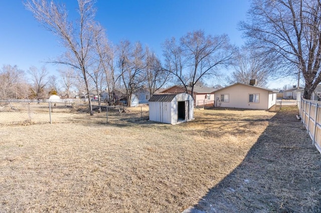 view of yard with an outbuilding, fence, and a shed