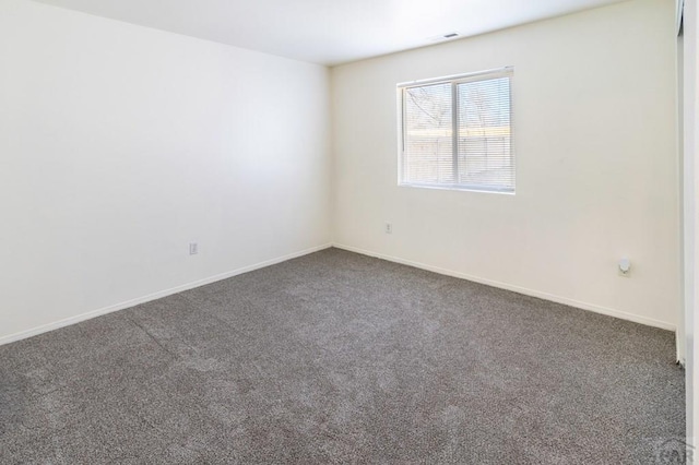 empty room featuring carpet and baseboards