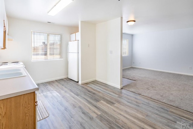 kitchen with a sink, baseboards, a wealth of natural light, and freestanding refrigerator