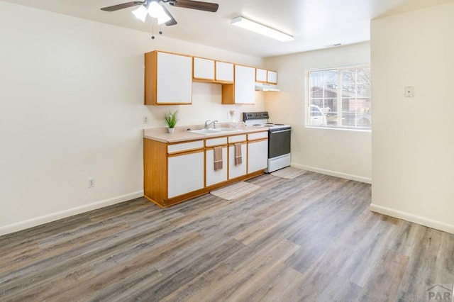 kitchen featuring baseboards, white range with electric cooktop, light countertops, light wood-type flooring, and a sink