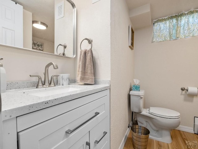 bathroom featuring visible vents, baseboards, toilet, vanity, and wood finished floors
