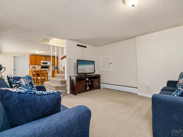living area with light colored carpet, a baseboard heating unit, a textured ceiling, and stairs
