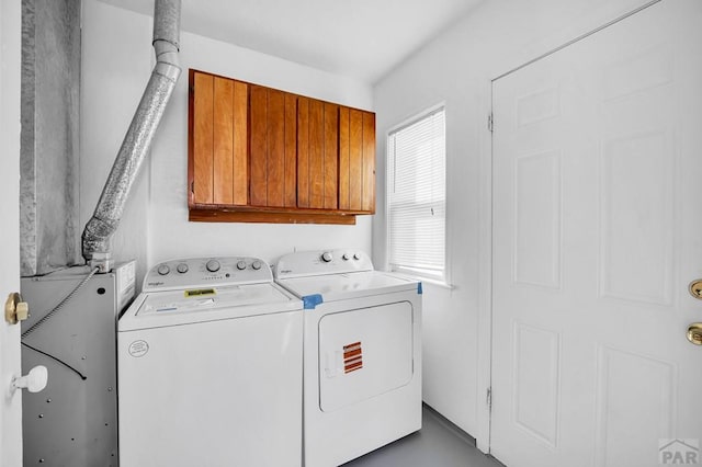 clothes washing area featuring cabinet space and washing machine and clothes dryer